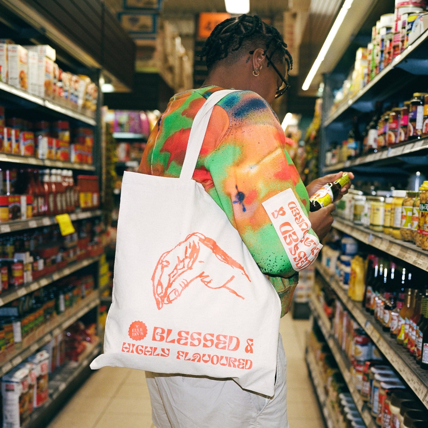 Black person at grocery store shopping for condiments with cool Elle Jay's tote bag