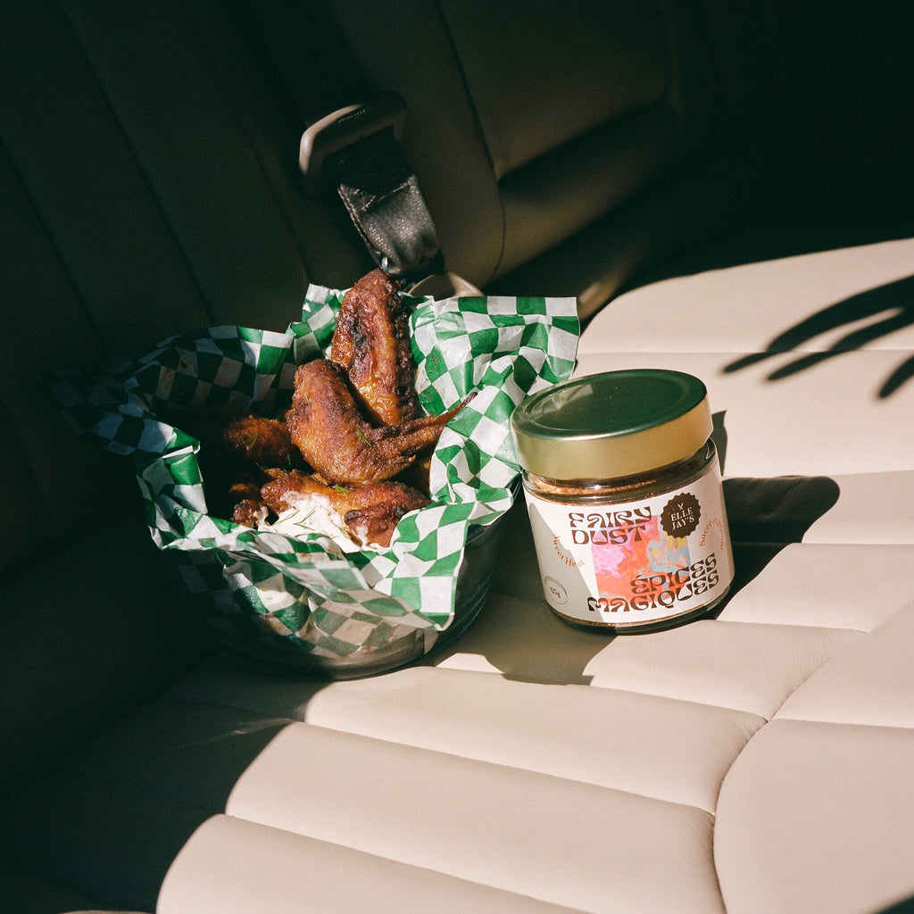 BBQ Spice blend with chicken wings on leather car seat with the shadow of a hand going to grab the jar